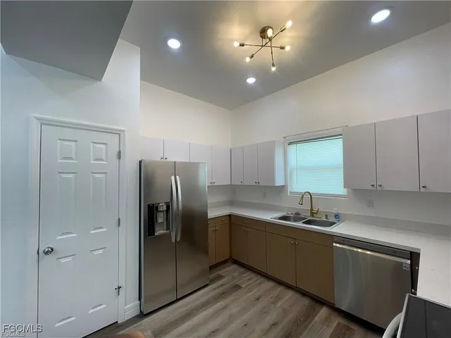 a kitchen with cabinets a sink stainless steel appliances and a window