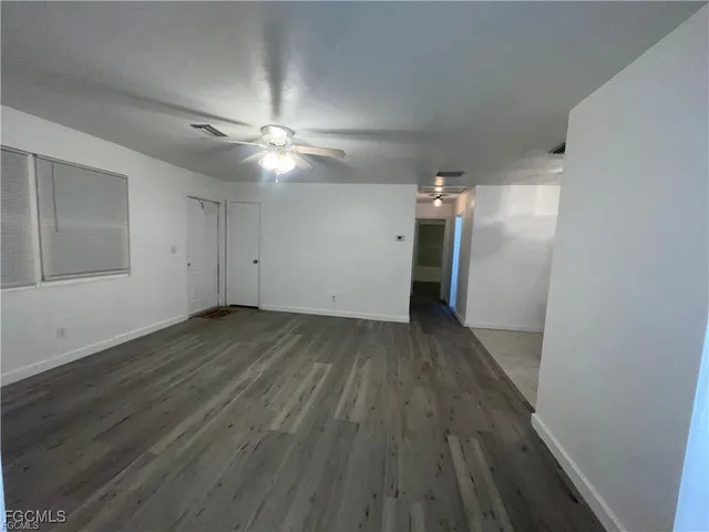 an empty room with wooden floor and a ceiling fan
