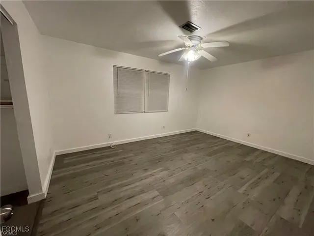 an empty room with wooden floor and fan