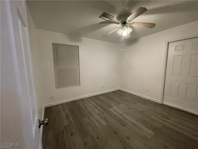 an empty room with wooden floor and fan