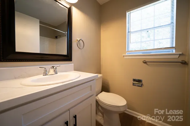a bathroom with a granite countertop toilet sink and mirror
