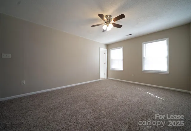 an empty room with windows and fan