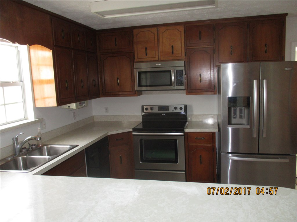 28296 Trigg Road Hilliard, FL 32046 - Photo 23 of 34 a kitchen with stainless steel appliances wooden cabinets a sink and a stove
