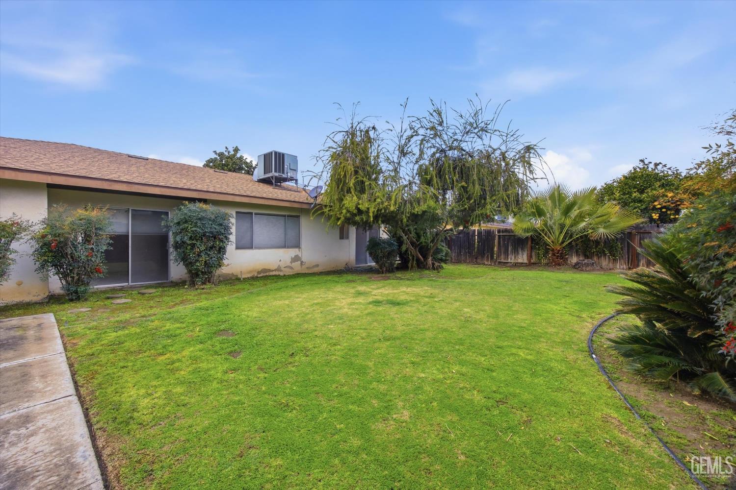 Undisclosed Address Bakersfield, CA 93309 - Photo 5 of 41 a backyard of a house with plants and large tree