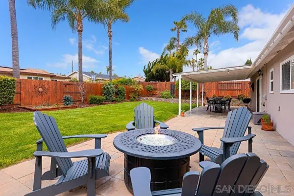 a view of a patio with table and chairs potted plants and a palm tree