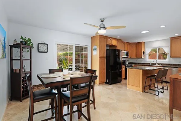 a kitchen with granite countertop a refrigerator a stove a dining table and chairs with wooden floor