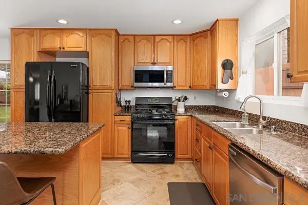 a kitchen with stainless steel appliances granite countertop a stove a sink and a microwave
