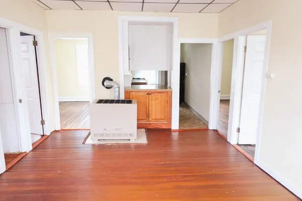 a view of a hallway with wooden floor and a bathroom
