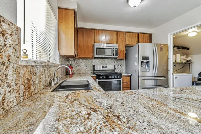 a kitchen with granite countertop a refrigerator and a stove top oven