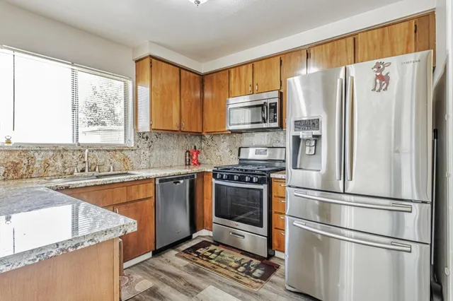 a kitchen with stainless steel appliances granite countertop a refrigerator sink and microwave