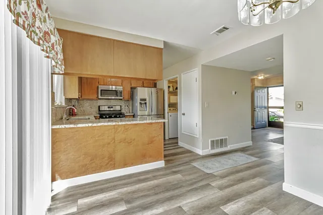 a view of kitchen with stainless steel appliances granite countertop a refrigerator and a sink