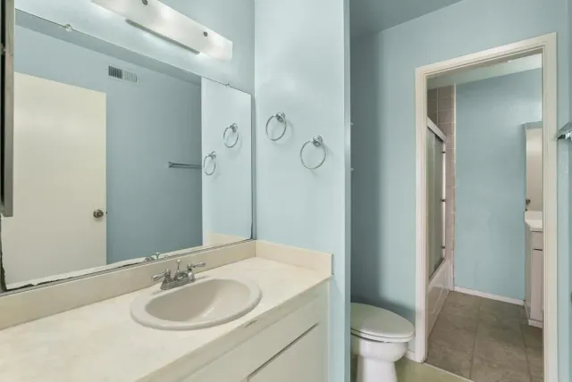 a bathroom with a granite countertop sink toilet and shower