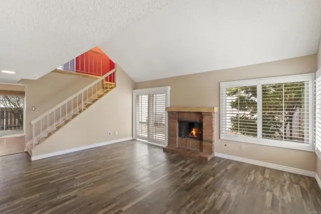 a view of empty room with wooden floor and fireplace