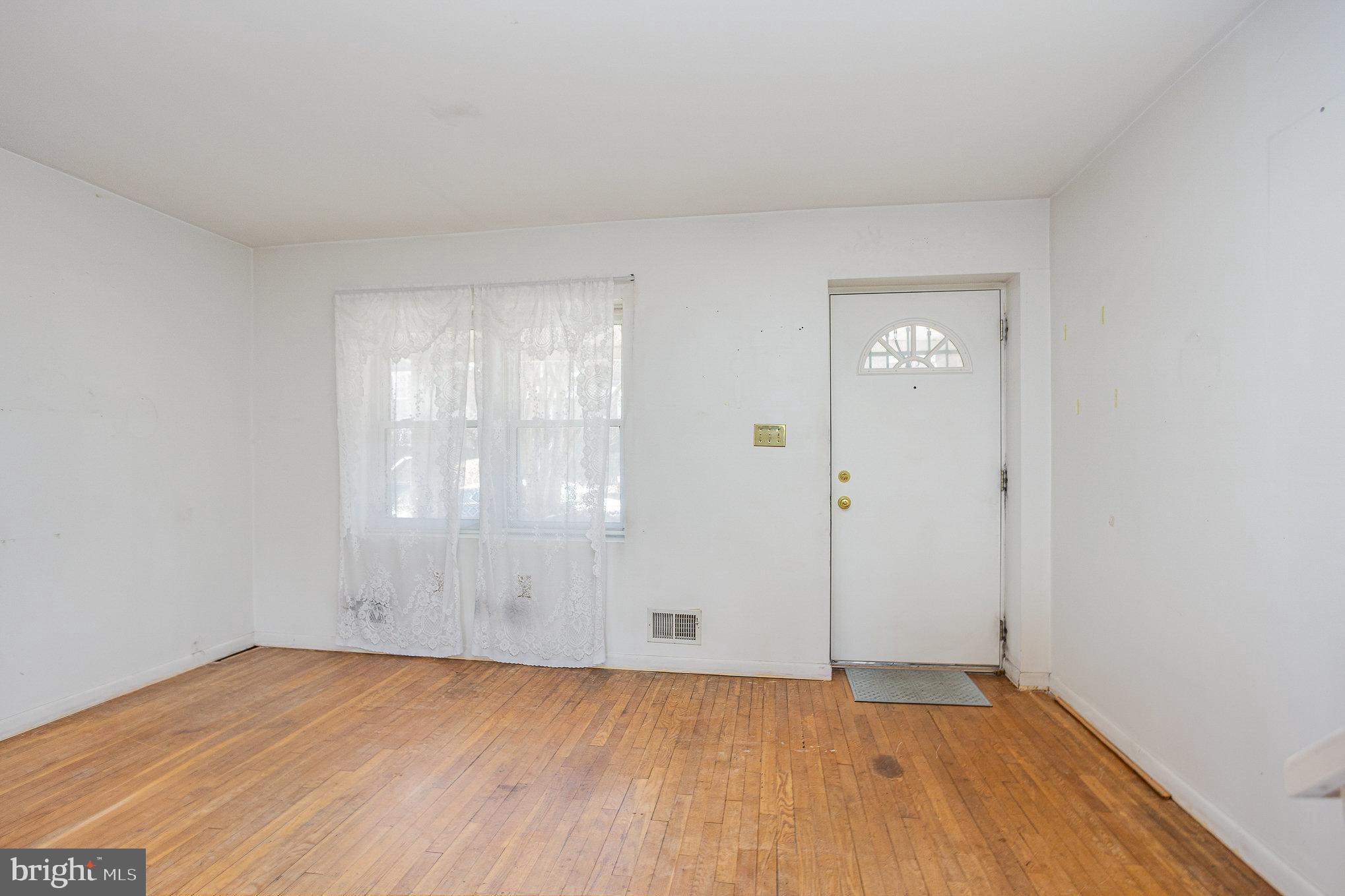 1408 Locust Street Curtis Bay, MD 21226 - Photo 4 of 25 an empty room with wooden floor and windows