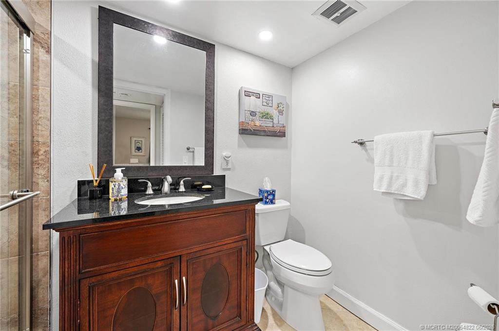 1862 Southwest Palm City Road, Unit 203 Stuart, FL 34994 - Photo 27 of 39 a bathroom with a toilet a sink a mirror a vanity and shower