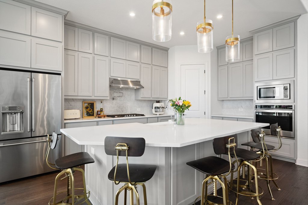 1221 Siena Sunset Road Leander, TX 78641 - Photo 19 of 39 Contemporary kitchen featuring light gray cabinetry, stainless steel appliances, a large central island with seating, pendant lighting, and dark wood-finish flooring