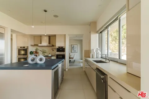 a kitchen with a sink a counter top space stainless steel appliances cabinets and a large window
