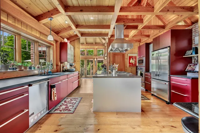 a kitchen with stainless steel appliances kitchen island granite countertop a table chairs in it and wooden floors