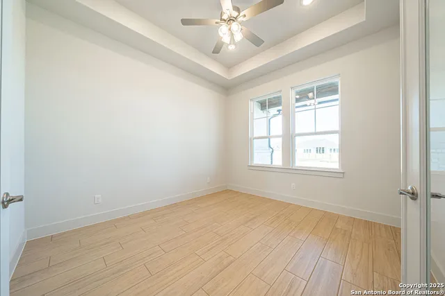 an empty room with a chandelier fan and windows