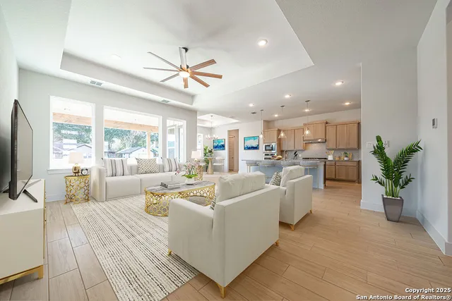 a living room with furniture kitchen view and a large window