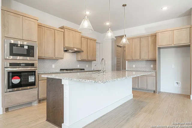 a kitchen with stainless steel appliances granite countertop a stove a sink and a refrigerator with white cabinets
