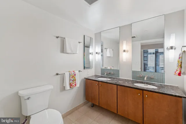 a bathroom with a granite countertop sink mirror vanity and toilet