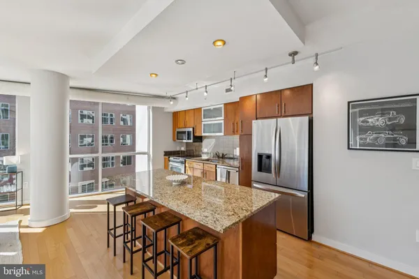 a kitchen with stainless steel appliances granite countertop a table chairs and a refrigerator