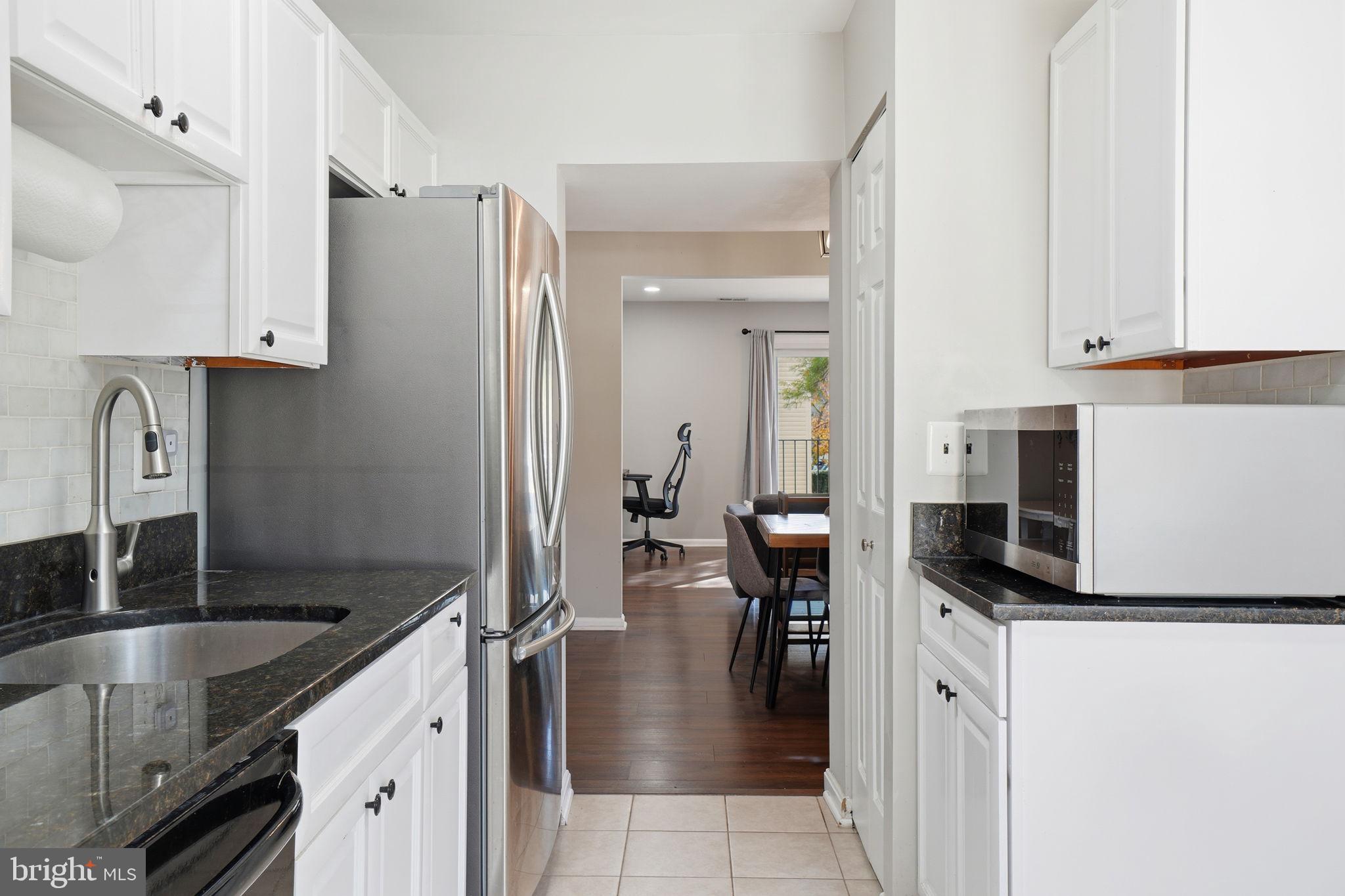 9175 Broken Oak Place, Unit 39B Burke, VA 22015 - Photo 14 of 35 a kitchen with stainless steel appliances granite countertop a refrigerator a stove and a sink with wooden floor