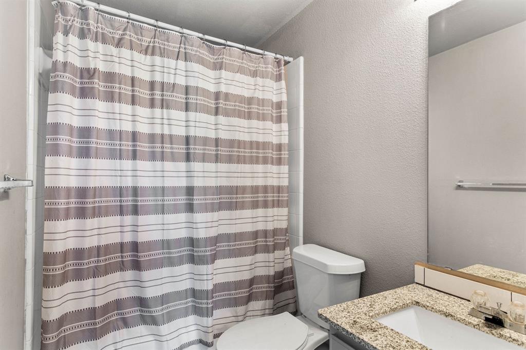 2700 Hereford Road Denton, TX 76210 - Photo 24 of 36 Bathroom featuring a vanity with granite-finish countertop and an integrated sink, a toilet, and a shower with a shower curtain rod