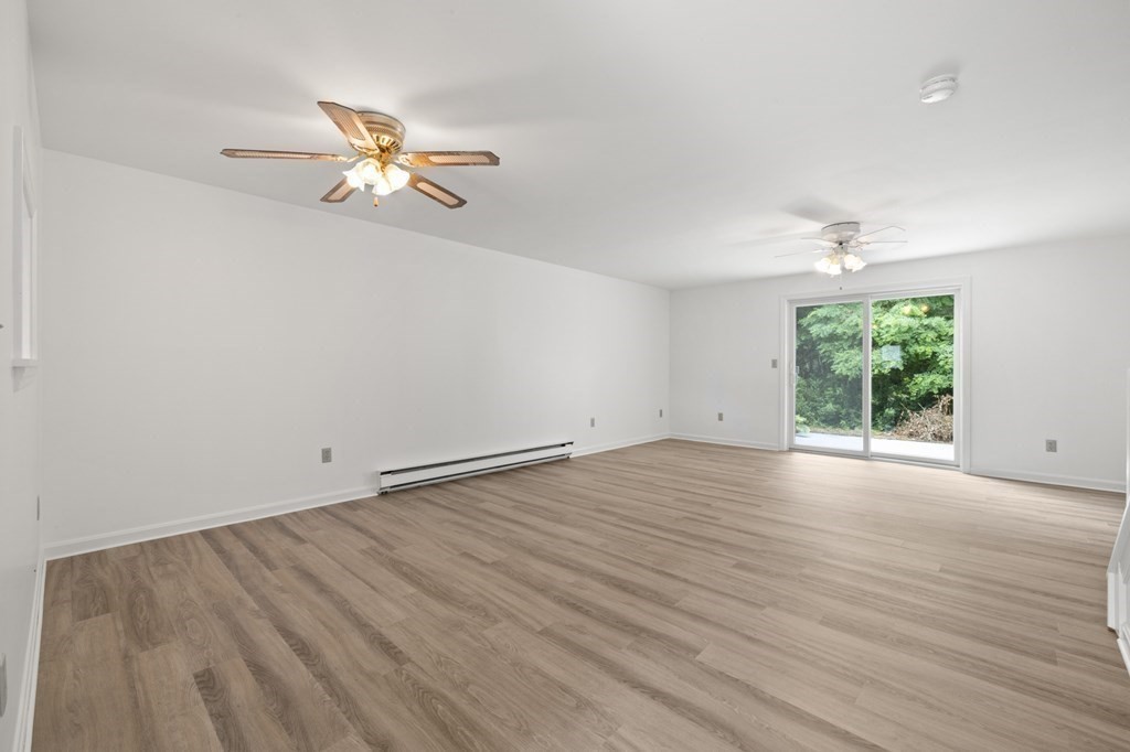 174 Lowell Road, Unit 135 Mashpee, MA 02649 - Photo 6 of 21 an empty room with wooden floor fan and windows