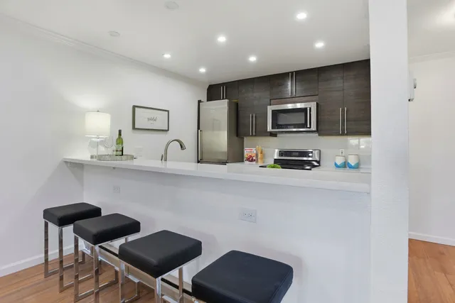a kitchen with table chairs refrigerator and microwave
