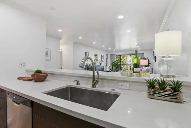 a kitchen with stainless steel appliances a sink a counter and a view of living room