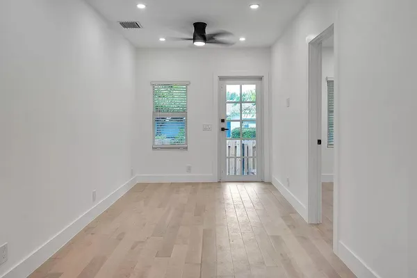 a view of an empty room with a window and wooden floor