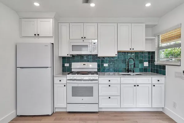 a kitchen with white cabinets and white appliances