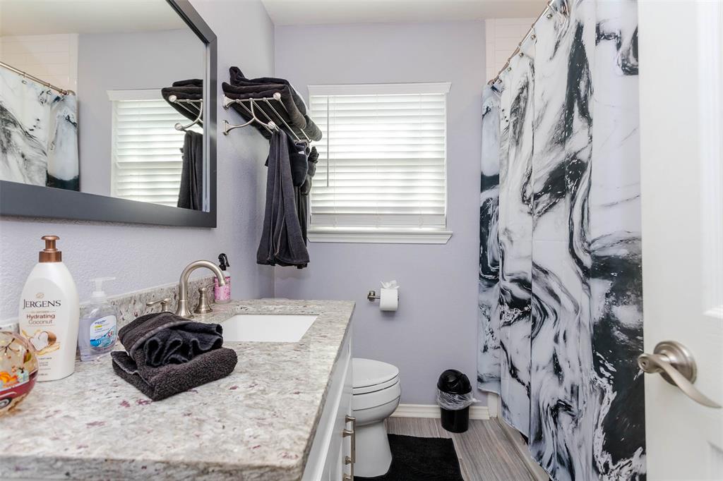 1333 South Pine Street Grapevine, TX 76051 - Photo 31 of 33 a bathroom with a granite countertop sink a toilet and shower curtain