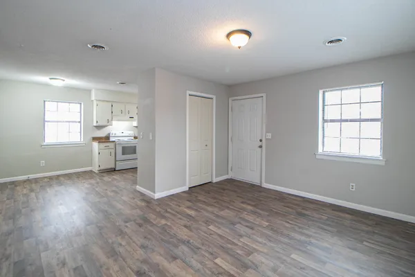 an empty room with wooden floor and windows