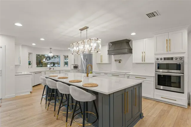 a kitchen with stainless steel appliances kitchen island granite countertop a dining table and chairs with wooden floor