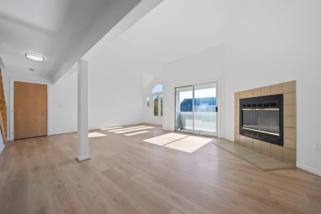 a view of empty room with wooden floor and fireplace