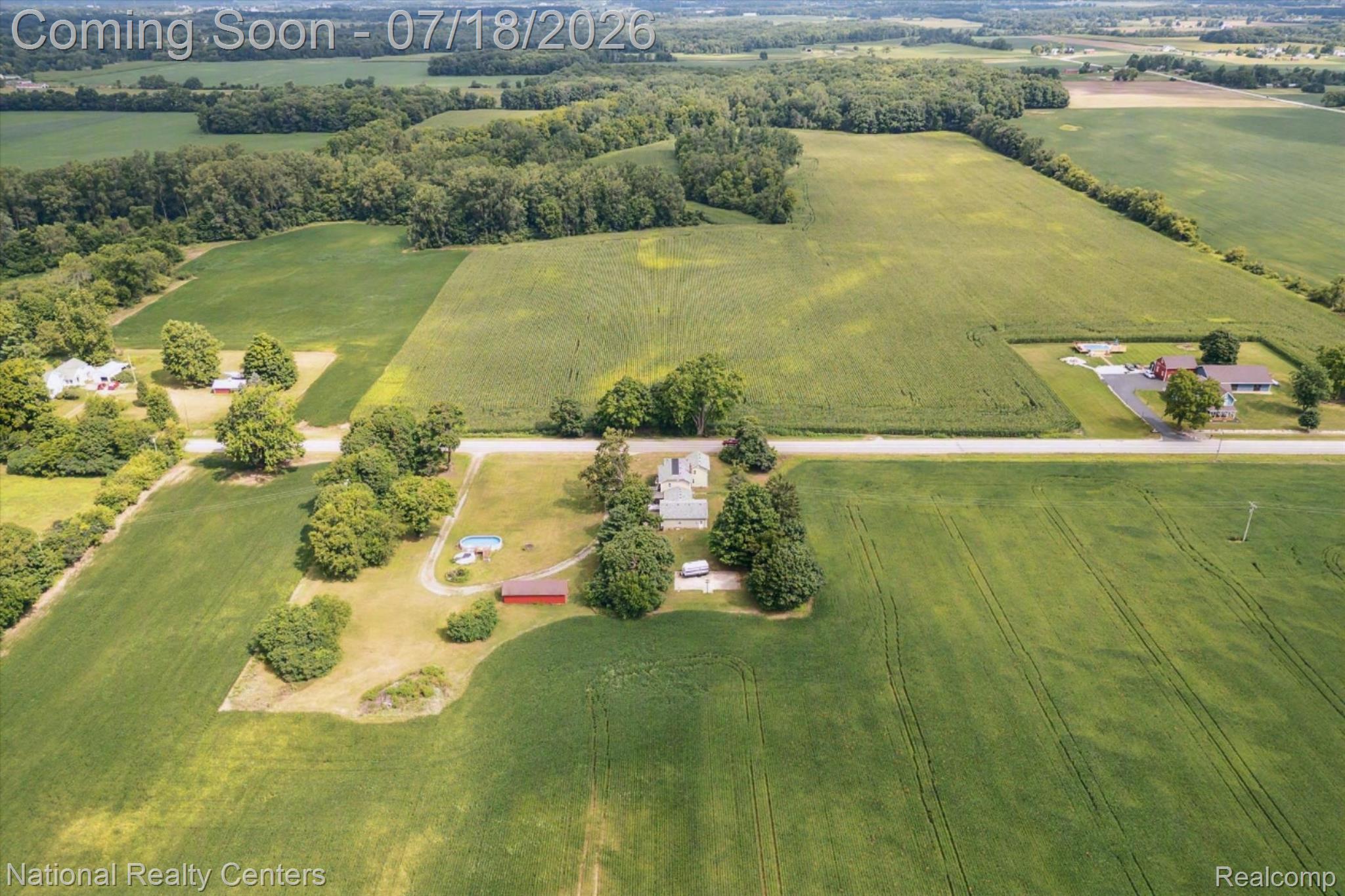 9589 Clinton Macon Road Tecumseh, MI 49286 - Photo 41 of 48 Expansive agricultural land featuring a central residential property with mature trees, a red outbuilding, and an above-ground pool