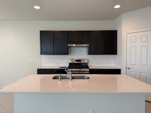 2015 Crimson Rosella Trail Austin, TX 78728 - Photo 4 of 20 Kitchen with decorative backsplash, light tile patterned floors, gas stove, a center island with sink, and recessed lighting