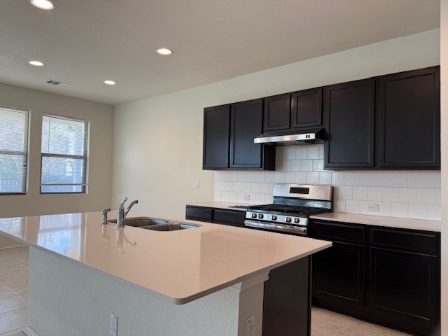 2015 Crimson Rosella Trail Austin, TX 78728 - Photo 6 of 20 Kitchen with stainless steel range oven, decorative backsplash, recessed lighting, light tile patterned floors, and an island with sink