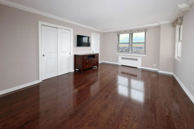 an empty room with wooden floor fireplace and windows