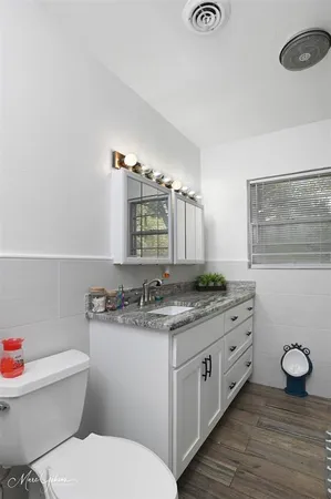 a bathroom with a granite countertop toilet sink and mirror