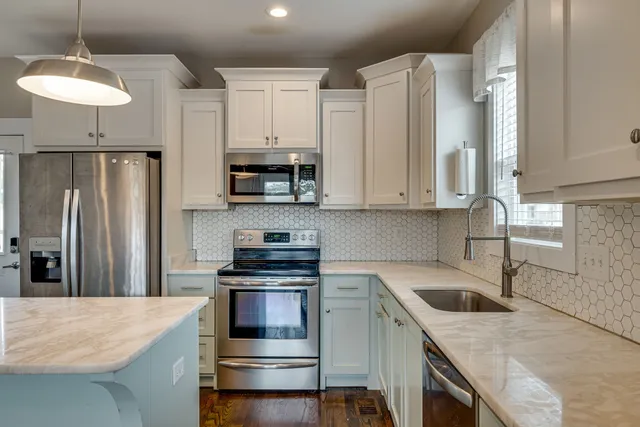 a kitchen with granite countertop a sink a counter space stainless steel appliances and cabinets