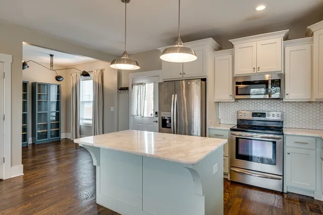 a kitchen with stainless steel appliances a stove a refrigerator and white cabinets