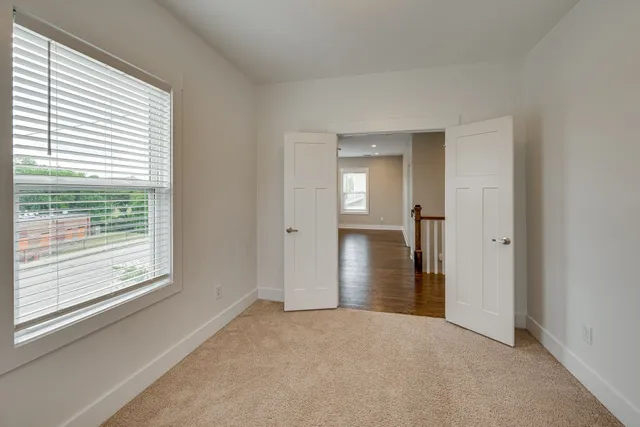 a view of an empty room with closet and a window