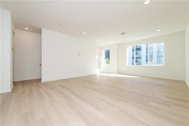 a view of an empty room and a kitchen