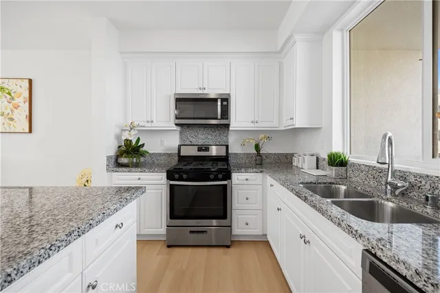 a kitchen with granite countertop a sink stove and cabinets