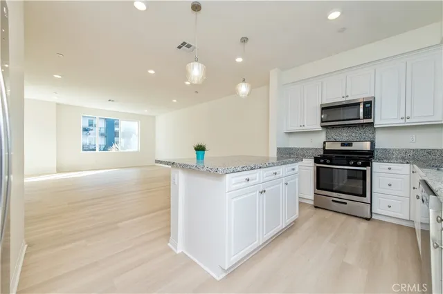 a kitchen with granite countertop white cabinets and stainless steel appliances