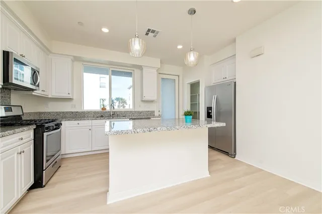 a kitchen with stainless steel appliances granite countertop a refrigerator and a stove top oven